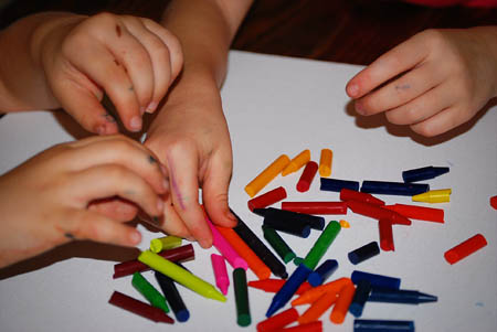 Little Toddler is collecting broken crayons at home